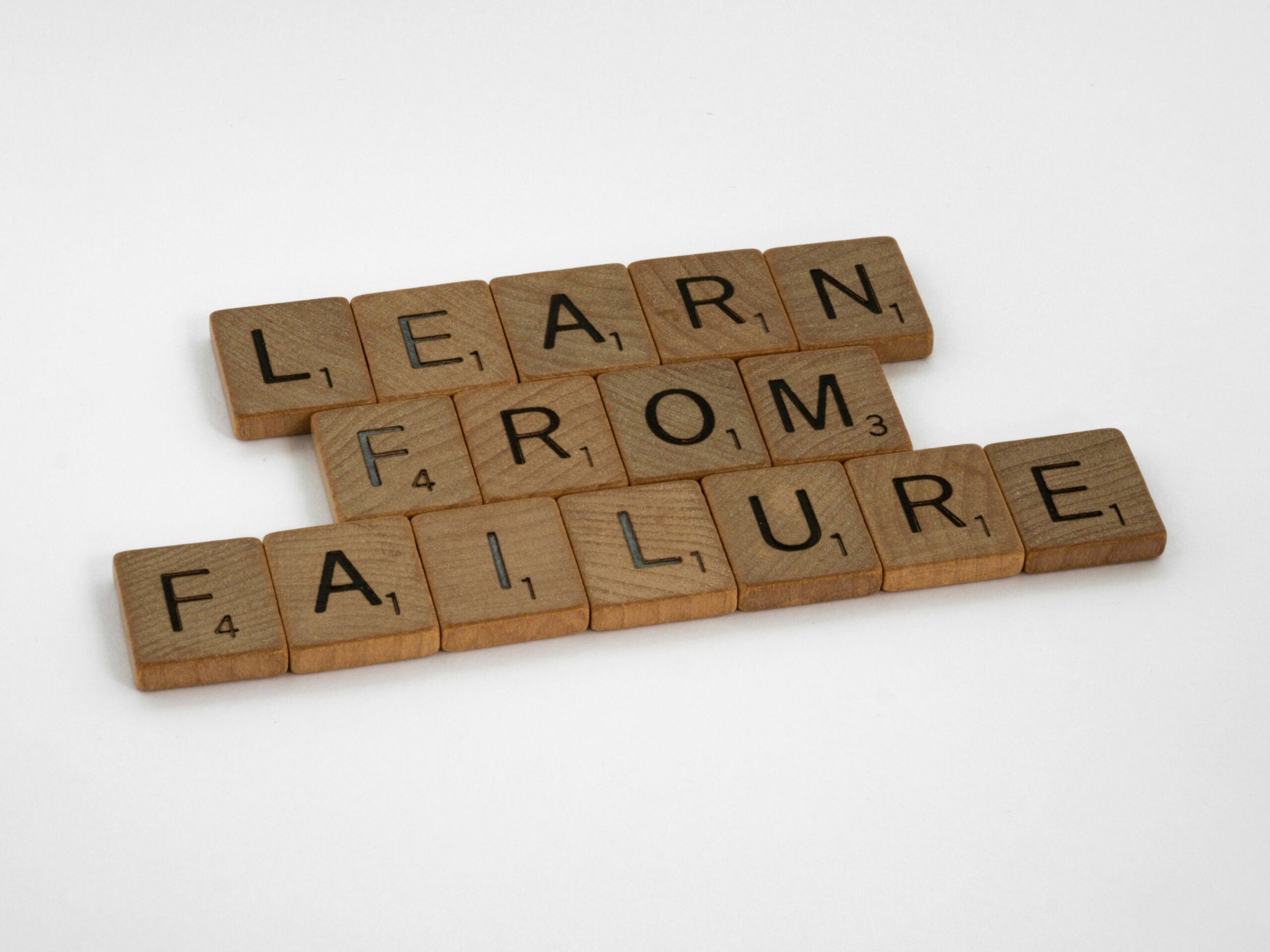 Scrabble alphabet tiles arranged on a board to spell out "learn from failure."